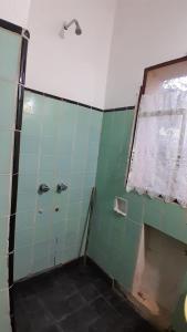 baño con ducha de azulejos verdes en Hostel Amarillo en San Ignacio