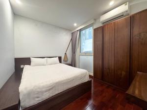 um quarto com uma cama branca e um armário de madeira em Nikomix - SAKAMOTO II Apartment - 2 Bedroom 60m2 em Hanói