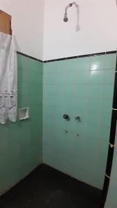 y baño con ducha y paredes de azulejos verdes. en Hostel Amarillo en San Ignacio