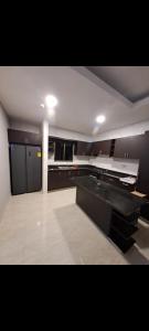 a large kitchen with black cabinets and a white floor at Kamehouse in La Arena