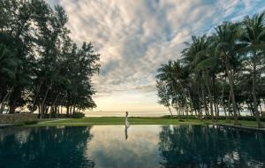 eine Person, die im Wasser neben einem Pool steht in der Unterkunft Dusit Thani Krabi Beach Resort - SHA Extra Plus in Klong Muang Beach