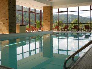 a swimming pool with tables and chairs in a building at Hotel Valea cu Pesti in Căpăţîneni-Ungureni