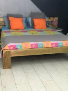 a wooden bed with orange pillows in a room at Petite halte O Cœur des Ilets in Bouillante