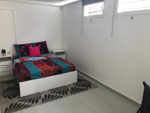 a white bedroom with a bed with a colorful blanket at Petite halte O Cœur des Ilets in Bouillante