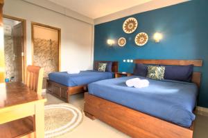 2 camas en una habitación con paredes azules en Hotel Bonne Nuit, en Labuan Bajo