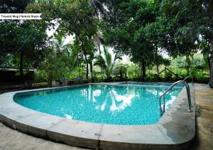 Rāmanagaram的住宿－Ambara Kovilakam Private Pool Villa by Travent Mug，一座树木繁茂的庭院内的游泳池