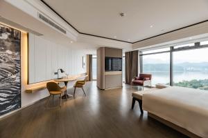 ein Hotelzimmer mit einem Bett, einem Schreibtisch und Stühlen in der Unterkunft Atour Hotel Tonglu Fuchunjiang in Tonglu