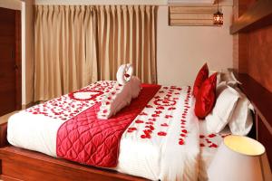 a red and white bed with red roses on it at Kuruva Island Resort And Spa - By KABINI BREEZE, Wayanad in Mananthavady