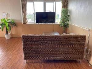 a living room with a wicker couch in front of a television at Green Garden Hills 3F-1 in Okinawa City