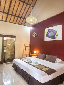 - une chambre avec un grand lit et un mur rouge dans l'établissement Trawangan Oasis, à Gili Trawangan