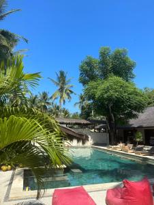 a swimming pool with chaise lounge chairs and palm trees at Trawangan Oasis in Gili Trawangan