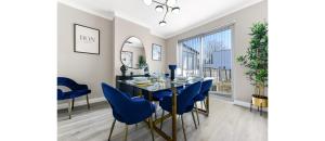 een eetkamer met een tafel en blauwe stoelen bij Serene, Stylish, Spacious Brand New for 2023! in Londen
