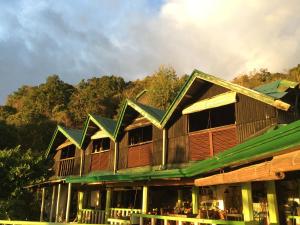 ein großes Holzgebäude mit grünem Dach in der Unterkunft Liberty's Community Lodge and Diving in Dumaguete