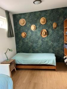 a bedroom with a bed with straw hats on the wall at huize Louwra in Egmond-Binnen