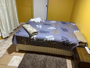 Una cama en una habitación con una manta azul. en Hostal La Mansion, en Antofagasta