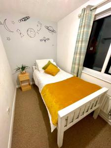 a bedroom with a bed with a yellow blanket and a window at 2 Bed Flat Privite in Canada Water in London