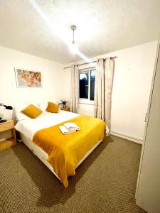 a bedroom with a bed with a yellow blanket at 2 Bed Flat Privite in Canada Water in London