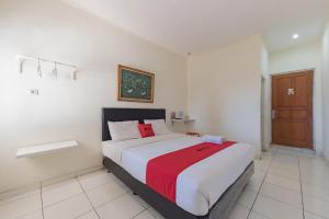 a bedroom with a large bed with a red blanket at RedDoorz Syariah @ Jl Raya Sukabumi in Sukaraja