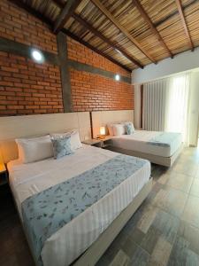 um quarto com 2 camas e uma parede de tijolos em La Colina Balance Hotel em Chinácota