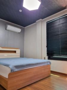 a bedroom with a bed and a window with black blinds at Food House in Andong