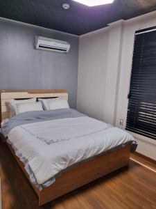 a bedroom with a large bed with white sheets and a window at Food House in Andong