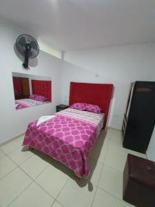 een slaapkamer met een roze bed en een ventilator bij HOSTAL GRAND IBIZA in Huacho