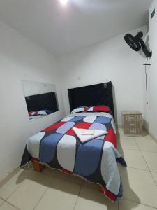 a bedroom with a bed with a red white and blue comforter at HOSTAL GRAND IBIZA in Huacho