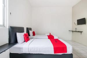 1 dormitorio con 1 cama blanca grande con almohadas rojas en RedDoorz Plus near Galaxy Mall, en Watulawang