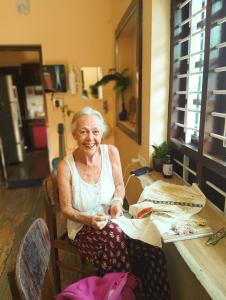 an older woman sitting at a table at Summer Beach House in Alleppey