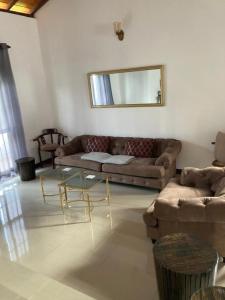 uma sala de estar com um sofá e uma mesa de vidro em ShaNicky Villa em Kandana