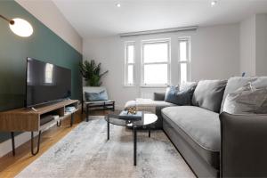 uma sala de estar com um sofá cinzento e uma televisão de ecrã plano em Travelers' Pad -Splendid Central Location! em Londres