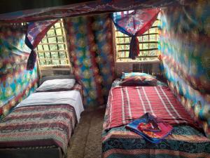 twee bedden in een kamer met gordijnen en ramen bij Glowing Mountain view tree house in Loanengo