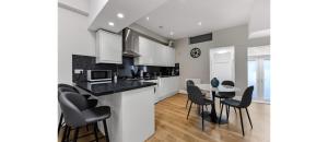 a kitchen with white cabinets and a table and chairs at Serene Escape: Stylish & Cozy 2BR Flat in London