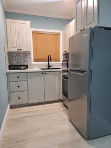 una cocina con nevera de acero inoxidable y armarios blancos en Sheer Bliss BeachView Apt #3, en Georgetown