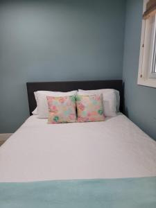 Una cama blanca con dos almohadas encima. en Sheer Bliss BeachView Apt #3, en Georgetown