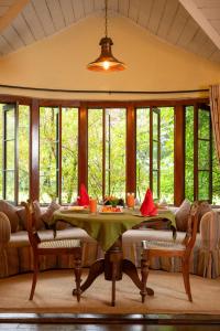 a dining room with a table and windows at Ferncliff Bungalow in Nuwara Eliya