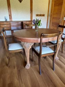 una mesa de madera con sillas y un jarrón de flores. en Le Bouquet Apart Hotel en San Carlos de Bariloche