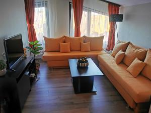 a living room with an orange couch and a table at Private Apartments in Hotel Snezhanka in Pamporovo