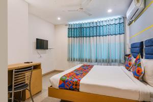 a bedroom with a bed and a desk and a television at FabHotel JKC Grand in Hyderabad