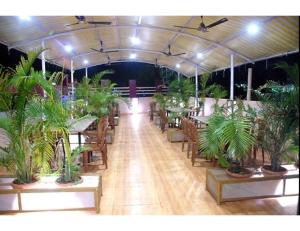 a room with tables and chairs with potted plants at Hotel Wardhman, Jabalpur in Jabalpur