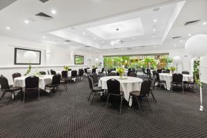 All Seasons Resort Hotel Bendigo في بنديجو: قاعة احتفالات بالطاولات البيضاء والكراسي السوداء