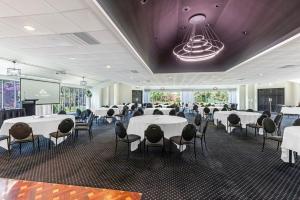 a banquet hall with white tables and chairs and a projection screen at All Seasons Resort Hotel Bendigo in Bendigo
