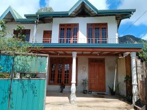 a house with a blue fence in front of it at Green Villa in Nuwara Eliya