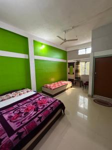 a bedroom with two beds and a green wall at Anuja Lodge 