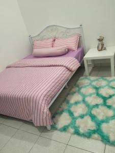 a bed with a pink and purple blanket and a table at Asmar's Homestay Alor Setar in Alor Setar