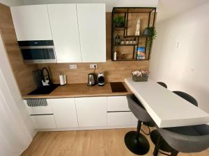 a kitchen with white cabinets and a table and chairs at PannaRoza Apartman in Balatonlelle +18 photos