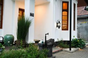 ein weißes Haus mit einer Eingangstür und einer Pflanze in der Unterkunft BUMINAKURA in Bandung