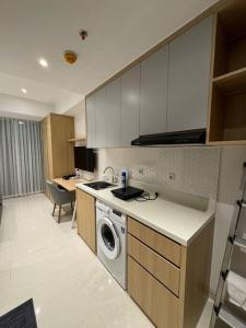 a kitchen with a washing machine in a kitchen at West Vista Studio Apartment with Netflix in Jakarta