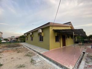 ein kleines gelbes und grünes Haus mit einer roten Backsteineinfahrt in der Unterkunft Homestay Selayang D Kepong in Kuala Lumpur