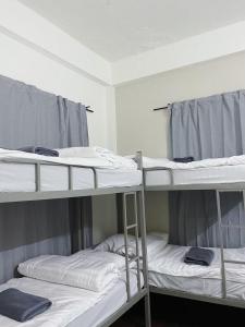 three bunk beds in a dorm room with towels at Tolomhouse in Hat Yai